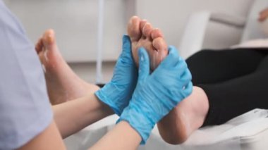 Lastik eldivenli masör bir kadına ayak masajı yapıyor.. 
