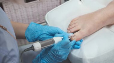 Güzellik salonunda bir pedikür uzmanı profesyonel bir donanım pedikürünü gerçekleştirmek için elektrikli matkap makinesi kullanır..