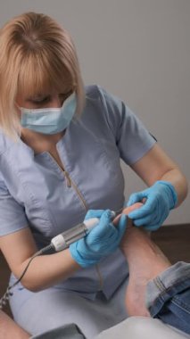 Ayak hastalıkları uzmanının portresi nasır aldırmak için bir değirmen makinesi kullanıyor