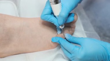 Pedikür ustası, kadınların ayak parmaklarını kesmek için matkap kullanıyor.