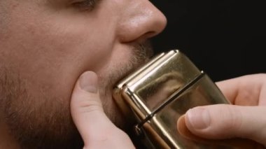 Genç bir adam lüks bir berber dükkanında bıyık kestiriyor. Kuaför, yüz kıllarına dikkat etmek için tıraş makinesi kullanır.