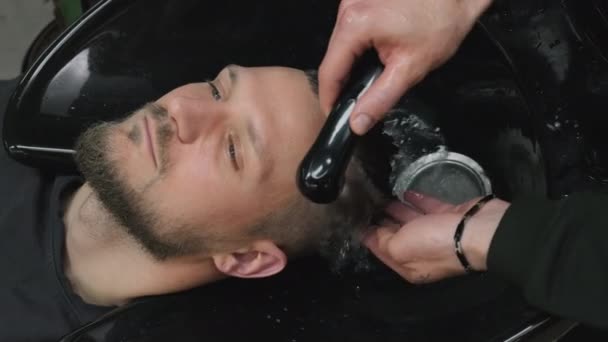 理发师在美发厅用水流洗掉客户的泡沫头发 有魅力的男人拜访专业理发师 卫生程序 — 图库视频影像