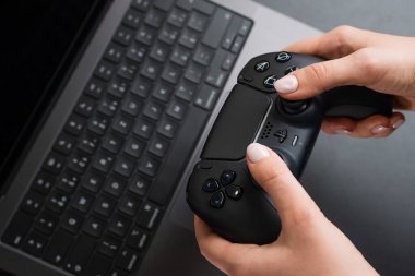 BERLİN, Almanya - 14 Şubat 2024: MacBook Pro 'nun yanında elinde video kontrol cihazı tutan kadın