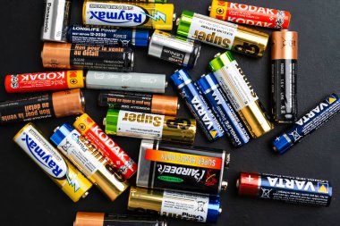 BERLİN, GERMANY - 14 NİSAN 2024: Siyah masanın üzerinde AAA, AA, CR2, 9 Volt büyüklüğünde küçük kullanılmış alkalin piller.