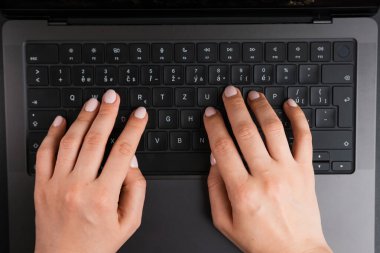 BERLİN, GERMANY - 14 NİSAN 2024: MacBook Pro 'nun klavyesinde kadın elleri, üst görünüm 