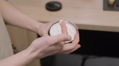 İnsan cildini nemlendirmek için kavanozdan krem alır. Erkek kişi evde vücut bakımı için kozmetik ürünler kullanıyor. Güzellik rutini