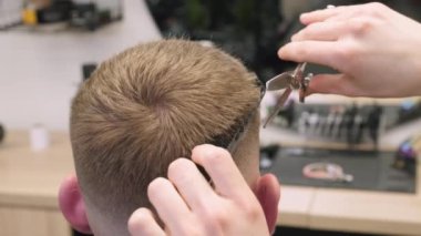 Berber, berber dükkanında müşterinin saçını makyaj aynası ile tarar. Kuaför kuaför kuaför kuaförde şık saç kesimi yapmak için makas kullanıyor.