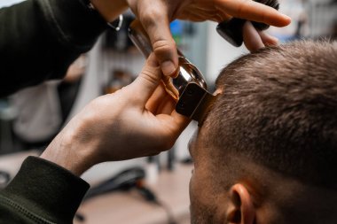 Barber uses an electrical trimmer to shave the clients hair in the sleek, contemporary barbershop