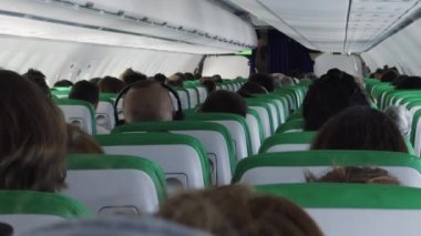 Yolcu grubu uçuşta rahat koltuklara sakince oturur. Gezginler uçakla yurt dışına güvenli yolculuğun tadını çıkarıyorlar. Havacılık servisi