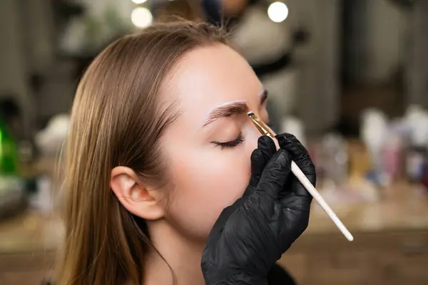 stock image Close up beauty master doing a conturing for brow dying for young lady. 