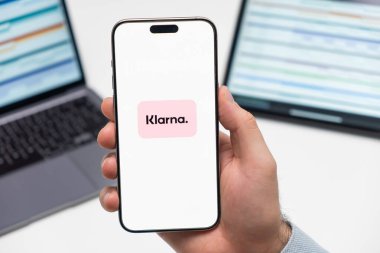 PRAG, CZECH REPUBLIC - 21 Ocak 2024: Klarna logosu, erkek elinin iş arka planındaki akıllı telefon ekranında. 