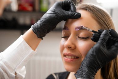 Bir kadının kaşları bir profesyonel tarafından kaplanıyor.