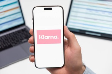 PRAG, CZECH REPUBLIC - 21 Ocak 2024: Klarna logosu, erkek elinin iş arka planındaki akıllı telefon ekranında. 