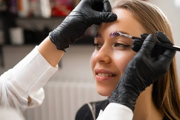 stock image A woman receives a brow lamination procedure from a professional