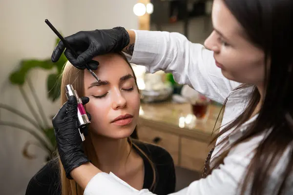 stock image Beauty master styling clients eyebrows in a salon. 