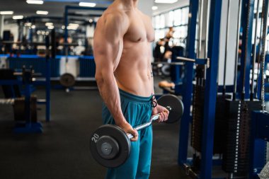 Vücut geliştirici spor salonunda halter kullanarak ağırlık kaldırır.