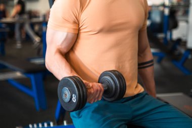 Spor salonundaki antrenman sırasında sporcunun elleri ağırlık kaldırır.