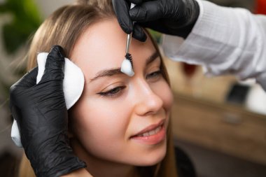 Kaş sanatçısı müşteriye kaş kaplama prosedürü uyguluyor. Yetenekli kadın kaşlarını şekillendirmek için farklı kompozisyonlar uyguluyor.