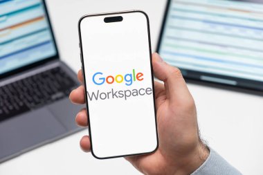 PRAG, CZECHIA - JULY, 2024: GoGoogle Çalışma Alanı Çalışma Alanı logosu, arka planda erkek eli ve dizüstü bilgisayardaki akıllı telefon ekranında 