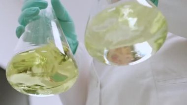 Analizden önce sarı örnekleri sallayan bir kimyagerin alt görüntüsü.