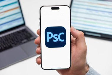 PRAG, CZECH REPUBLIC - 21 Ocak 2024: Adobe Photoshop Kamera logosu, erkek elinin akıllı telefon ekranında işyeri arka planında. 