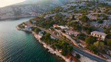 Yolcu vagonu gün batımında deniz kenarında dar bir şasi boyunca ilerliyor. Doğal manzaralı ve havadan manzaralı küçük evleri olan bir tatil yeri.