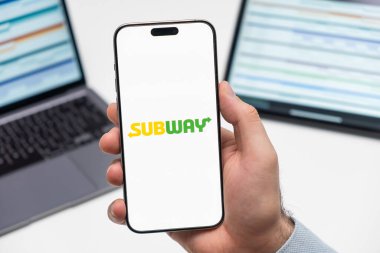 PRAG, CZECHIA - Temmuz 2024: Arka planda insan eli ve dizüstü bilgisayarda akıllı telefon ekranında metro logosu 