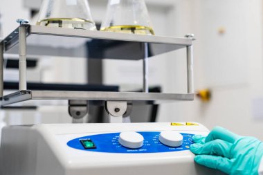 Lastik eldivenli kimyager laboratuardaki karıştırıcıya örnek yerleştiriyor.