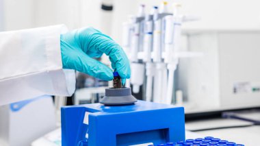 HPLC analizinden önce girdap karıştırıcı kullanarak numune sallayan bir kadının fotoğrafını çek.
