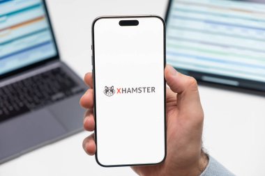 PRAG, CZECHIA - HAZİRAN, 2024: xHamster logosu erkek eli ekranda ve arka planda dizüstü bilgisayar 