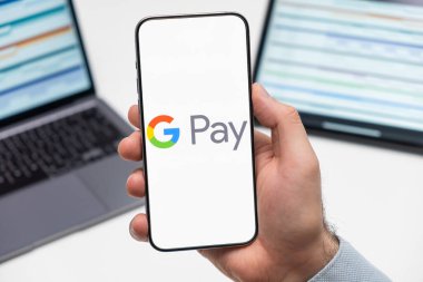 PRAG, CZECHIA - Temmuz 2024: Google, arka planda erkek eli ve dizüstü bilgisayardaki akıllı telefon ekranında ödemeli logo 