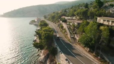 Çatıda SUP tahtası olan araba uçurum boyunca gökyüzü denizine doğru gidiyor. Turistler su sporlarından zevk almak için kıyı boyunca seyahat ederler.