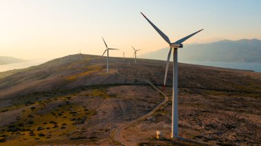Rüzgar türbinleri gün batımında Adriyatik Denizi ile çevrili Pag Adası 'nda çevre dostu güç üretiyor.. 
