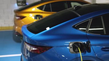 Arka planda sarı araba olan elektrikli araba yeraltı otoparkında şarj edildi. Hava kirliliğinden kaçınmak için modern şehir otomobilleri kavramı