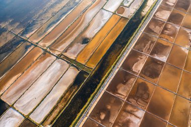 Parlak güneş ışığı altında değişik dokulara ve desenlere sahip renkli tuz tavalarının havadan görünüşü. 