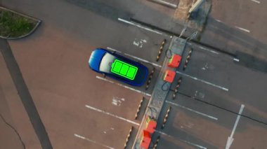 Otoparktaki halka açık şarj noktasına bağlı elektrikli arabanın çatısında parlayan pil göstergesi. Otomatik olarak uzun bir yolculuk için elektrik alır