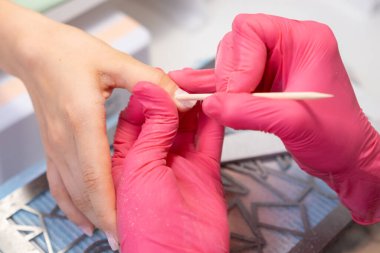 Manikür ustası, Cuticula profesyonel müşterilerinin parmaklarını kesmek için turuncu çubuk kullanır.. 