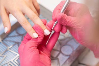 Manikürü jöle cilasıyla detaylandırmak için manikürcüde küçük bir fırça kullanmak. Manikürcü jel cilasını düzeltmek için küçük bir fırça kullanır.