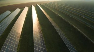 Geniş alana parlayan güneş panelleri sisli gündoğumunda güneş ışınlarını yansıtır. Güneş ışığını kırsal kesimde elektriğe dönüştürmek için yenilikçi ekipmanlar