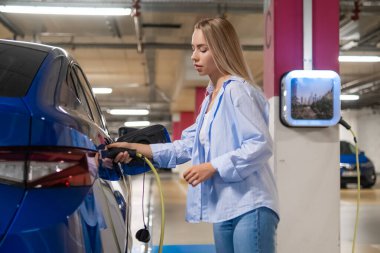 Bir kadın, gün ışığında yeraltı otoparkına girdiği için elektrikli araba takıyor.. 