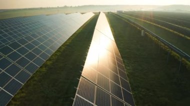 Güneş ışınları alan hava görüşüne yerleştirilmiş uzun güneş panelleri. Sisli şafakta kırsal alanda yeşil enerji üretmek için yenilikçi ekipmanlar