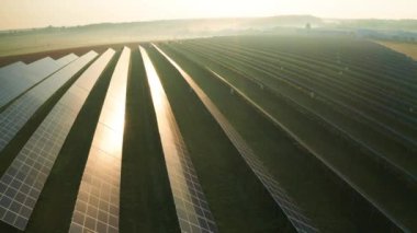Şafakta sislerin içinde yeşil enerji için güneş panelleri olan büyük bir alan. Modern ekipman, güneş ışığını yakalayarak havadan elektrik görüntüsüne dönüştürüyor