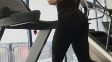 Çoraplı genç kadın baldır kaslarını güçlendirmek için koşu bandı kullanıyor. Sıska kadın makinede yavaş koşar ve kalori yakar. Spor salonunda kilo verir.