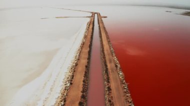 Torrevieja gölü kuş bakışı pembe tuz tabakaları boyunca kayalık yol kenarları. Renkli suyu ve beyaz bankası olan İspanyol turistik ve endüstriyel konumu