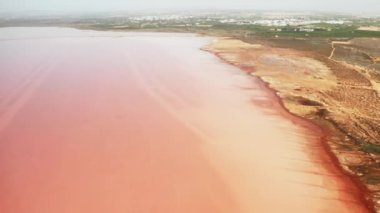 Sisli şehir manzarasına karşı dev pembe tuz gölü. Renkli Torrevieja su deposu. Endüstriyel taş ocakları ve iyileşme merkezleri var.