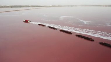 Sürat teknesi, pembe tuz Torrevieja gölü hava manzaralı kargo mavnası taşıyor. Su mavnası kullanarak renk suyundan mineral birikintileri çıkarmak