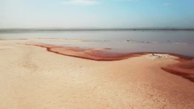 Torrevieja Gölü 'nün temiz gökyüzü manzarasının altında boş pembe plaj. İyileştirici İspanyol tatil köyünü ziyaret ederken doğa güzelliği tefekkür