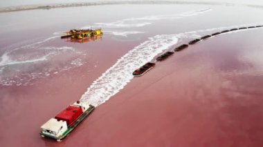 Sürat teknesi, Torrevieja gölü kuş bakışı pembe tuz platformunda kargo mavnalarını çekiyor. Sudan doğal mineral birikintileri çıkarılıyor.