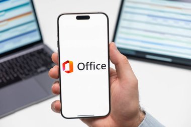 PRAG, CZECHIA - 2024 Temmuz: Microsoft Ofisi 365 logosu arka planda erkek eli ve dizüstü bilgisayarda akıllı telefon ekranında 
