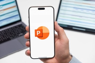 PRAG, CZECHIA - Temmuz 2024: Arkaplanda akıllı telefon ekranında Power Point logosu ve arka planda dizüstü bilgisayar 